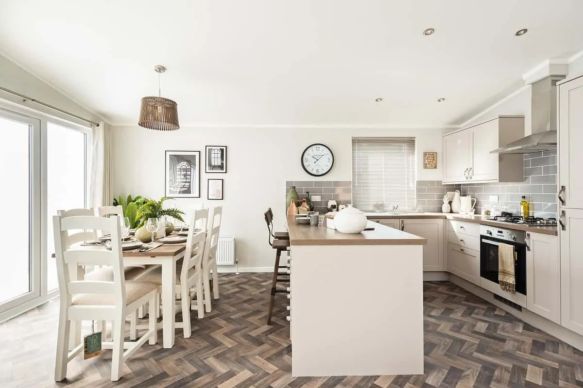 Spacious kitchen and dining area with white cabinetry, large island, herringbone flooring, and modern decor.