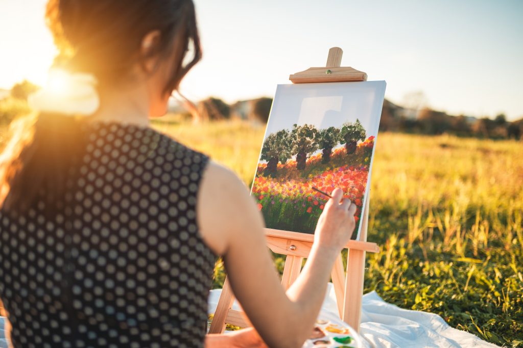 Happy girl painting outdoors on canvas at seunset Happy girl painting outdoors on canvas at seunset