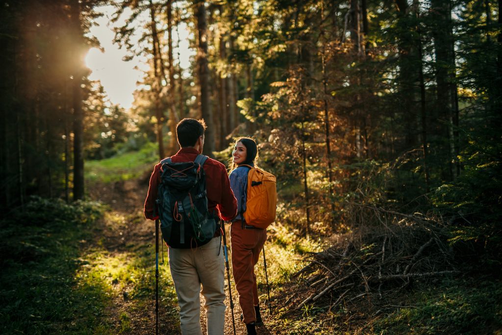 Couple with backpacks hiking together in forest during sunset Inspire lodge Living space